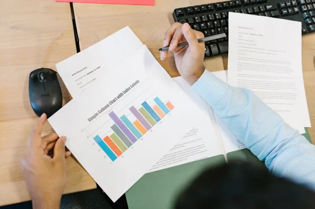 A business analyst reviews a colorful bar chart and documents at a desk, indicating data analysis. Creator career paths metrics: what to track
