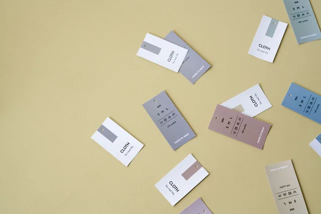 Floating clothing tags in various colors against a yellow backdrop with ample copy space. Reading the merchandise examples closely
