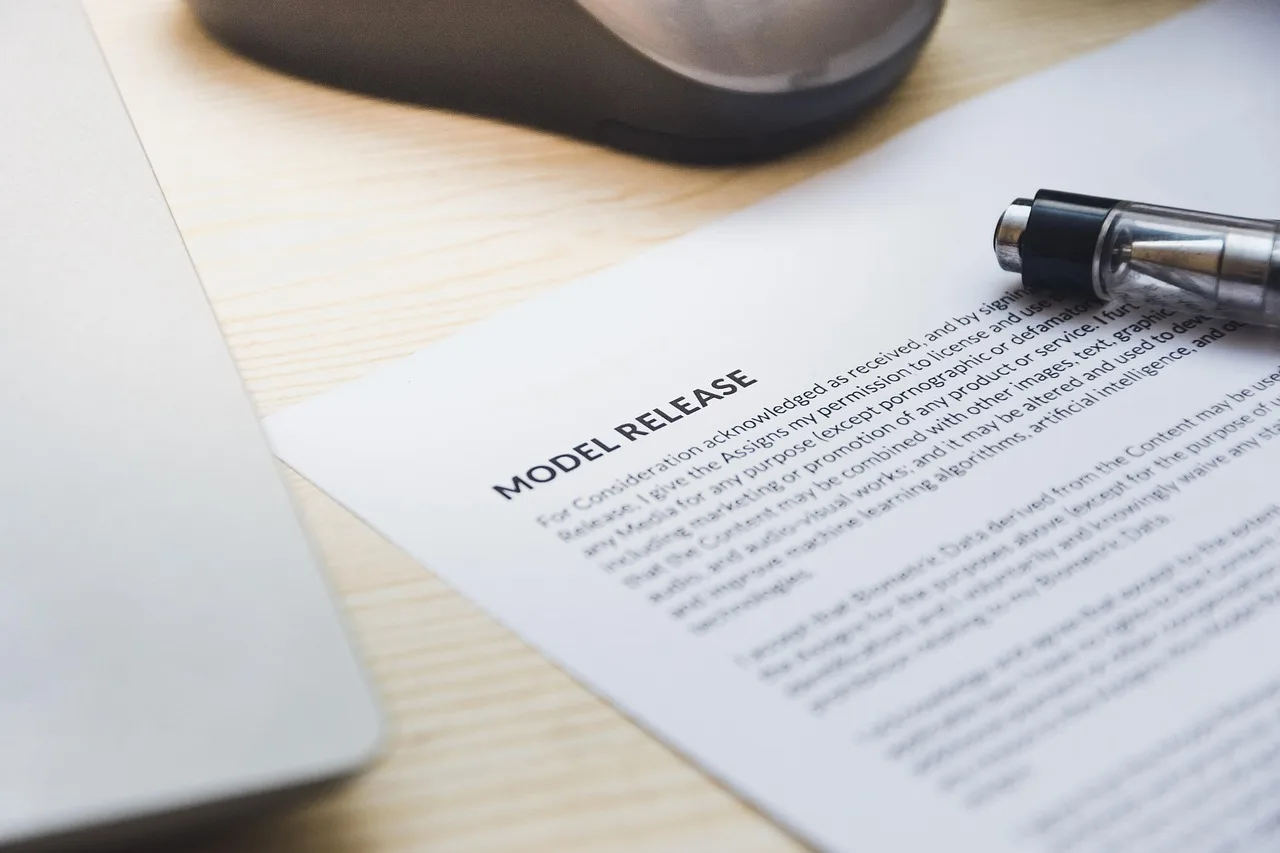 paper, model release, form, document, signing, pen, desk, agreement, business, contract, signature. Ever scroll through New York creator contracts?
